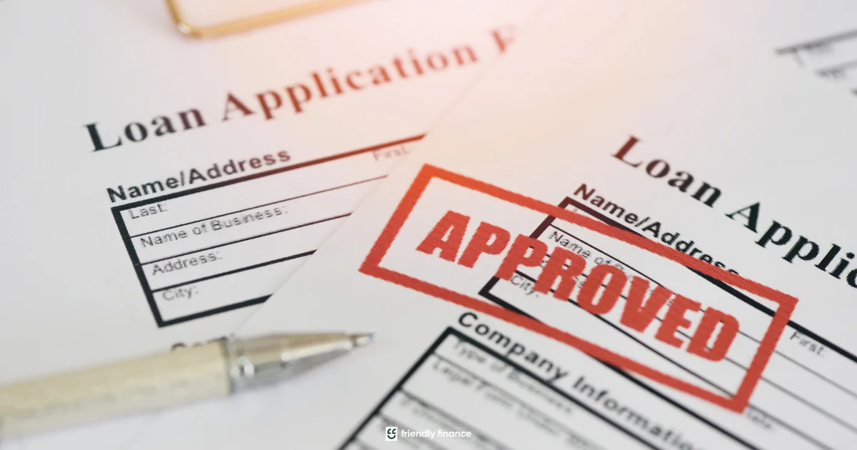 A close-up of a loan application form with a large red 'APPROVED' stamp on it, next to a pen.